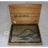 A JAPANESE SILVERED WHITE METAL PLAQUE, engraved and cast in relief with a mountain and clouds,