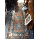 A TRADITIONAL RED GROUND PERSIAN RUNNER with central blue diamonds, 35" wide x 168" long