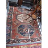 A RED GROUND PERSIAN RUG with three central panels and geometric decoration, 56" x 73"