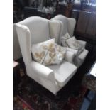 A PAIR OF CONTEMPORARY WING BACK ARMCHAIRS upholstered in cream material