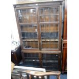 A 1920S OAK BOOKCASE with leaded glazed doors and carved grotesque decoration, 76" high x 43" wide