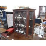 AN EDWARDIAN GLAZED MAHOGANY WALL CABINET with canted sides, 25.5" high x 27.5" wide