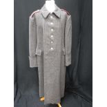 A GENTLEMAN'S DARK GREY LONG WOOLLEN SINGLE BREASTED OVERCOAT with gold coloured decorative