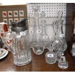 A GLASS LEMONADE JUG with a plated mount and a collection of cut glass decanters