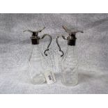 A PAIR OF SILVER PLATED AND CUT-GLASS OIL AND VINEGAR BOTTLES with acanthus leaf scroll handles,