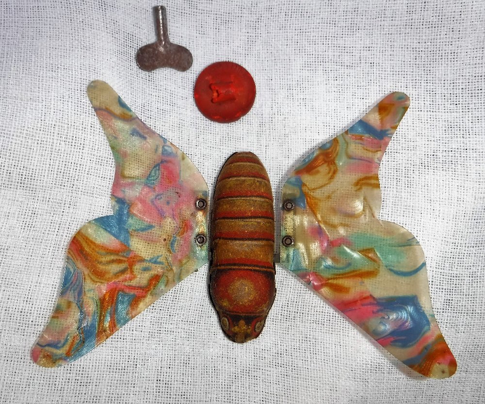 A VINTAGE GERMAN TIN PLATE CLOCKWORK BUTTERFLY with multi-coloured celluloid wings (with key) 4"