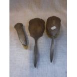 A THREE PIECE SILVER-BACKED DRESSING TABLE SET with a mirror and two brushes