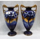 A PAIR OF POTTERY VASES decorated in blue and gilt with Art Nouveau flowers