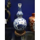 AN ORIENTAL BLUE AND WHITE BOTTLE VASE, 8" high on a carved wooden stand