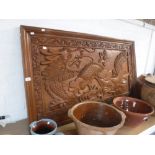 A LARGE ORIENTAL CARVED HARDWOOD PANEL depicting a dragon, 29" high x 51" wide