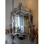 A VENETIAN MIRROR OF ELABORATE FORM with an applied cast metal grotesque, 22" wide