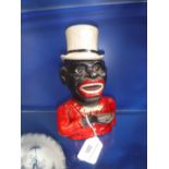 A CAST-IRON AND PAINTED MONEY BOX in the form of an African American wearing a top hat and red