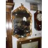 A GILT FRAMED WALL MIRROR OF CARTOUCHE FORM, 30" high x 18" wide