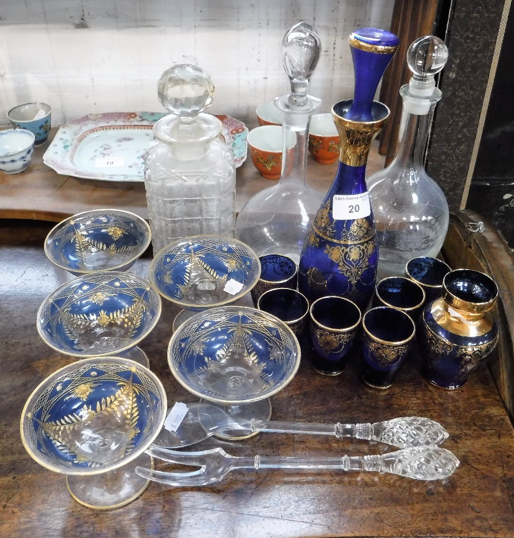 A BLUE GLASS DECANTER, with six glasses, overlaid with gilt decoration and similar glassware