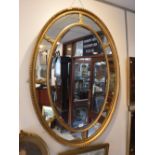 A LARGE OVAL GILT FRAMED WALL MIRROR, 44" high x 32" wide