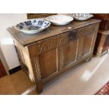 AN 18TH CENTURY OAK COFFER with carved decoration to the panelled front, 27" high x 43" wide