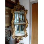 A GILTWOOD CORNER DISPLAY SHELF, with mirrored back, 43" high