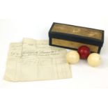 Boxed set of three Victorian ivory billiard balls including a stained red example, together with