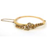 Unmarked gold diamond and seed pearl bangle set with thirteen diamonds and forty seed pearls,