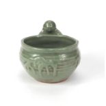 Oriental celadon glazed pot with a figure beside, 12cm high x 16cm wide