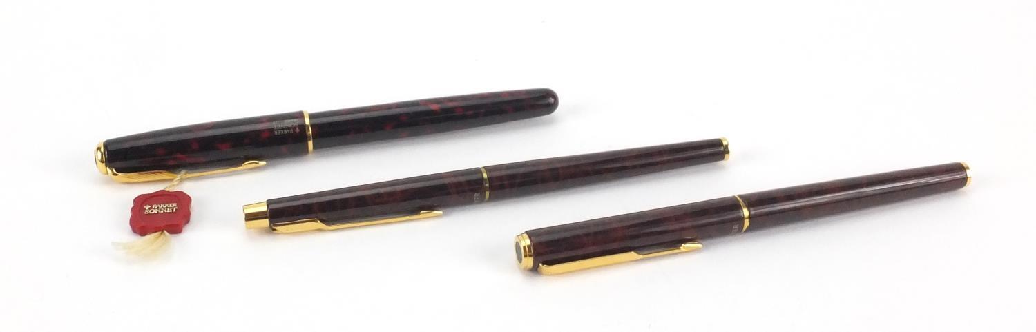 Parker red marbleised Sonnet fountain pen with 18k gold nib, together with two other Parker pens