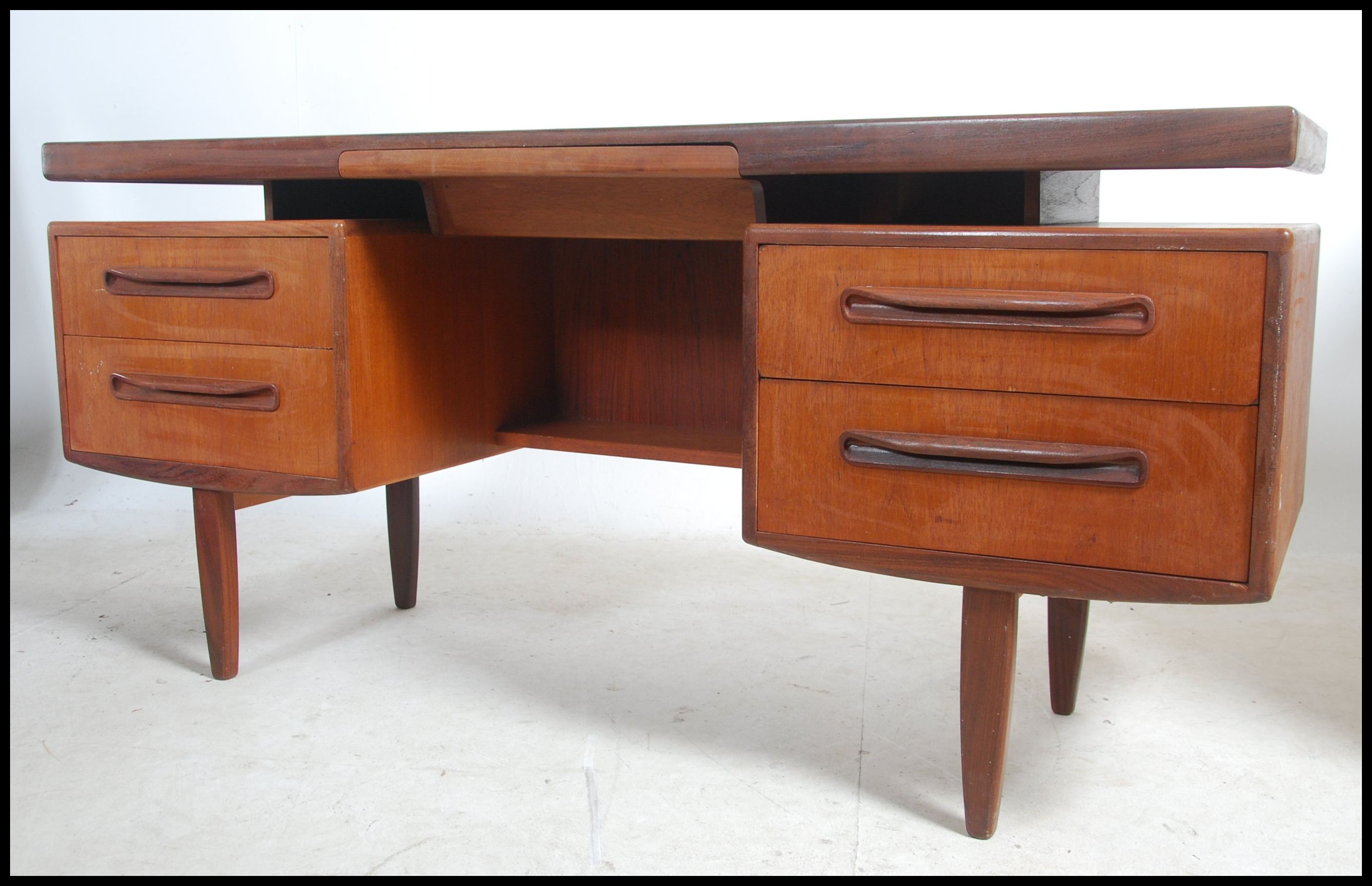 A 1970's G-Plan Fresco pattern teak wood writing table desk having a series of drawers with recessed