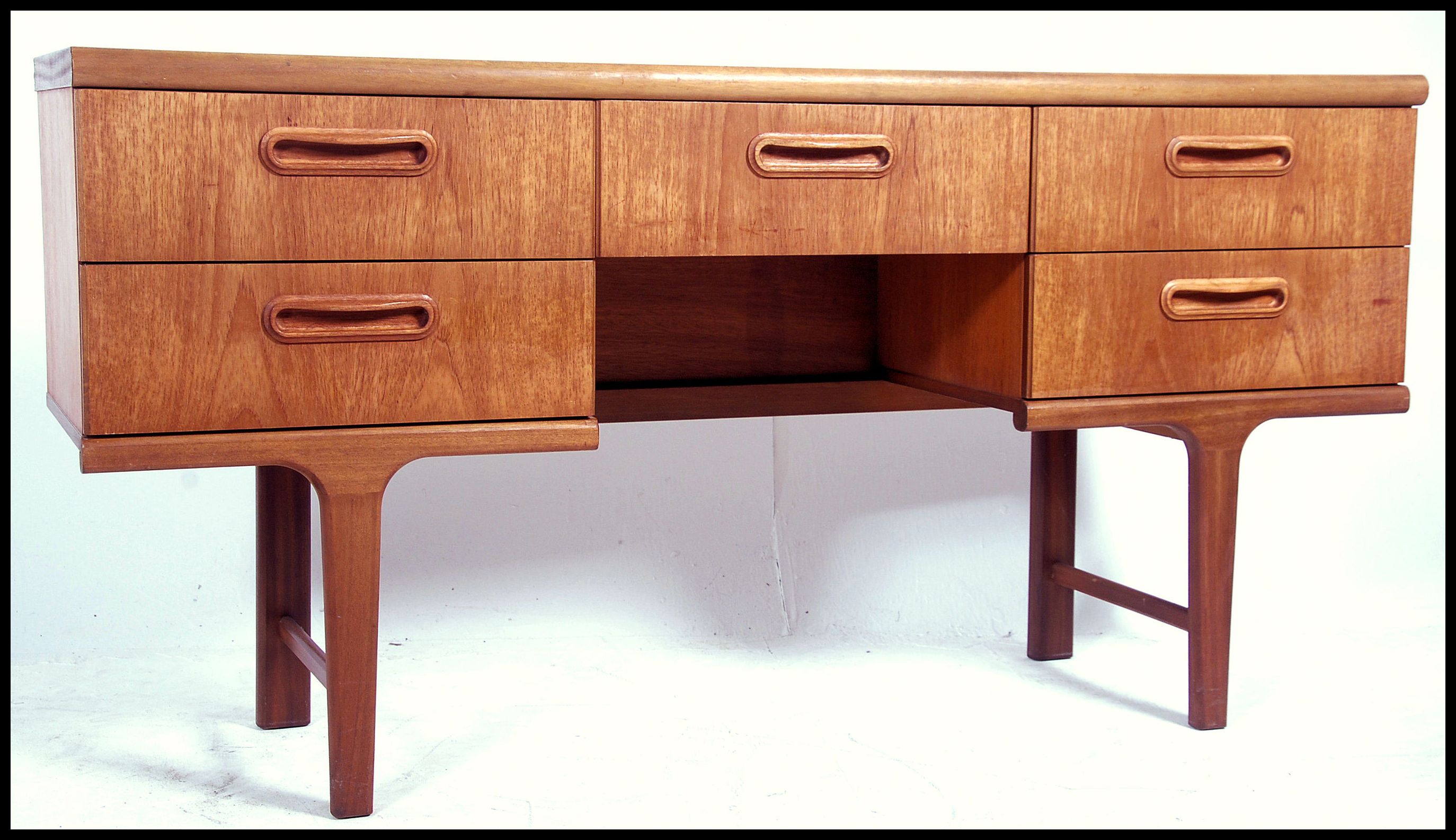 A 1970's Danish inspired retro teak wood writing table desk. The desk with central kneehole recess
