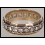 A 9ct gold eternity ring having a band of diamonds and sloped edges. Marked 9ct to the interior, all