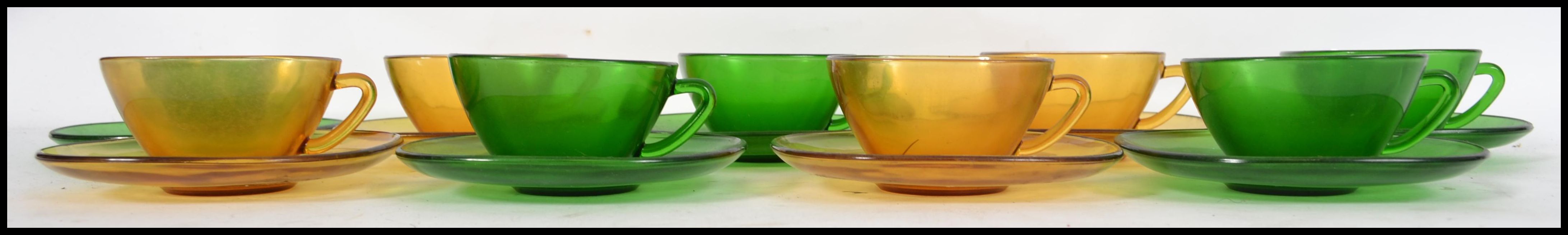 A group of eight French pressed coloured glass coffee cups and matching saucers