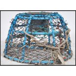A large 20th century Devon sea fishing lobster / clawfish pot having net and rope present in blue