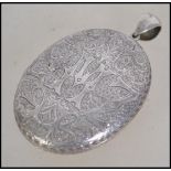 A Victorian large silver locket of oval form being chase decorated with hinged centre and bale atop.
