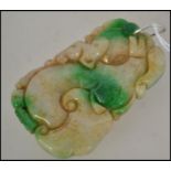 A Chinese jade carved pendant in the form of dragons / dogs of fu having a silver bale clasp atop.