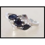 A white metal sapphire ladies ring. The ring with round cut sapphire flanked by 2 marquise cut