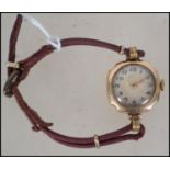 A 9ct gold 375 marked ladies dress watch being set to a leather strap. Decorative dial with
