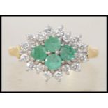 An 18ct gold, diamond and emerald ladies cluster ring. 4 central round cut emeralds surrounded by