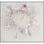 A silver charm bracelet containing many charms to include crown, slippers, animals, boat, horse,