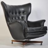 An original 1960's believed Parker Knoll black Batwing swivel chair - armchair being raised on