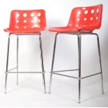 A pair of 20th century Robin day Skid Red bar stools being raised on tubular chrome frames with