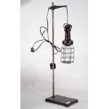 A vintage 20th century inspection lamp complete with wire cage raised on a cast metal base having