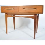A 1970's G-plan Kofod Larsen teak wood writing table desk being raised on tapered supports with