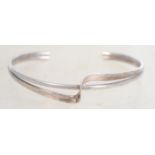 A sterling silver bangle bracelet of cross over fo