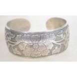 A heavy silver bangle bracelet having engraved fol