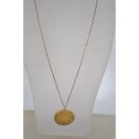 A sterling gilt silver coin pendant necklace on a