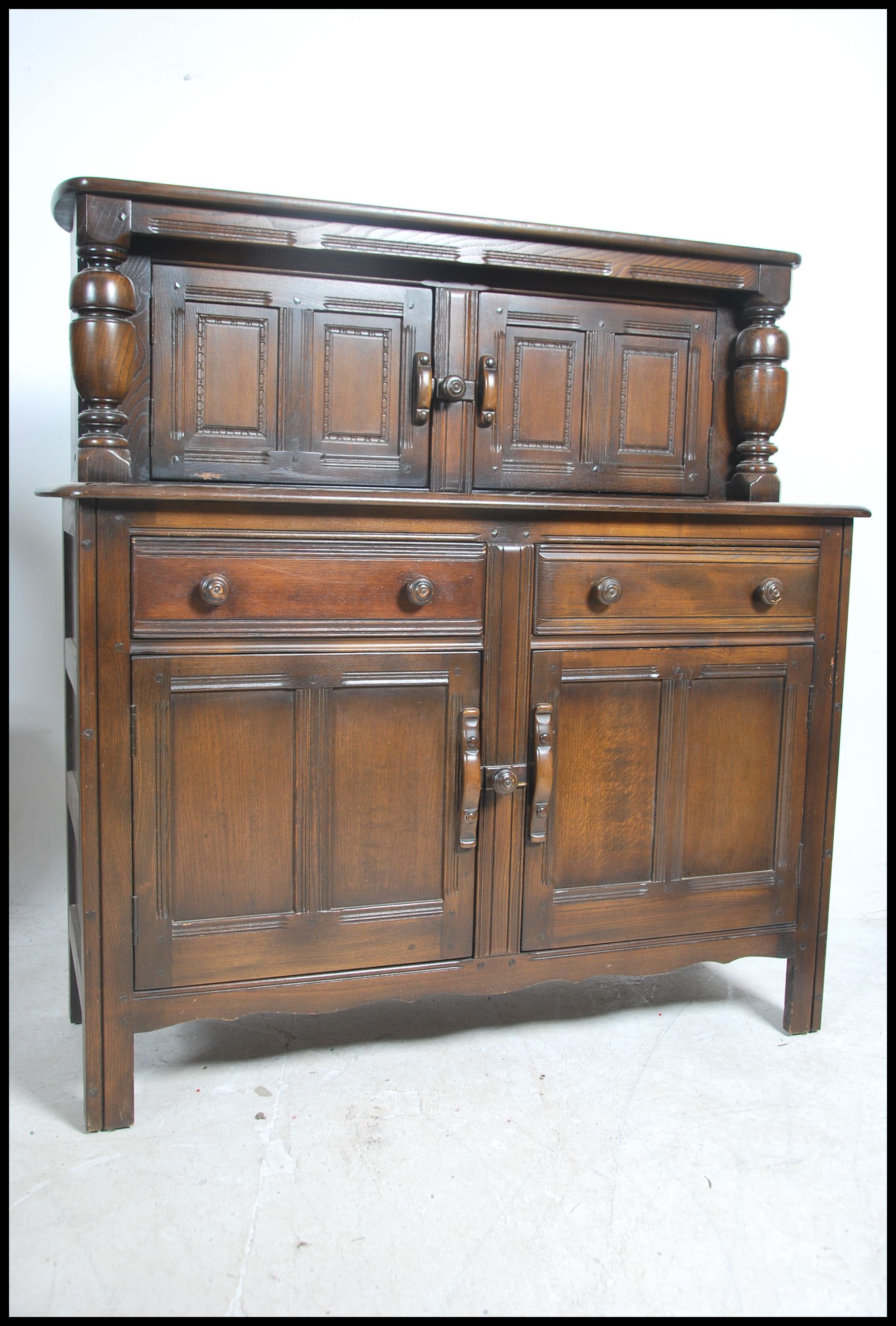 A 20th century Ercol court cupboard in beech and e