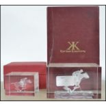 A pair of boxed glass paper weights each depicting a rider on horse playing polo by Karina