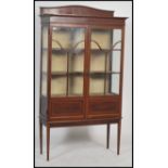 An early 20th century Edwardian marquetry inlaid twin astragal glass door display cabinet raised