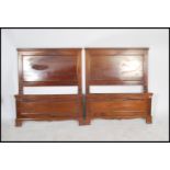 A pair of Edwardian mahogany single beds having panelled head and footboards being united by the bed