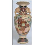 A large Japanese stoneware Satsuma vase being decorated with scenes of merchantmen. Twin handles