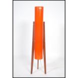 A 1970's retro teak atomic rocket lamp being raised on tapering supports with vibrant cylinder shade