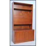 A 1970's retro teak wood upright bookcase having shaped shelves over fall front cabinet and cupboard